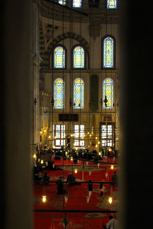 Free Peaceful mosque interior view with stained glass windows and people at prayer, capturing a sacred moment. Stock Photo