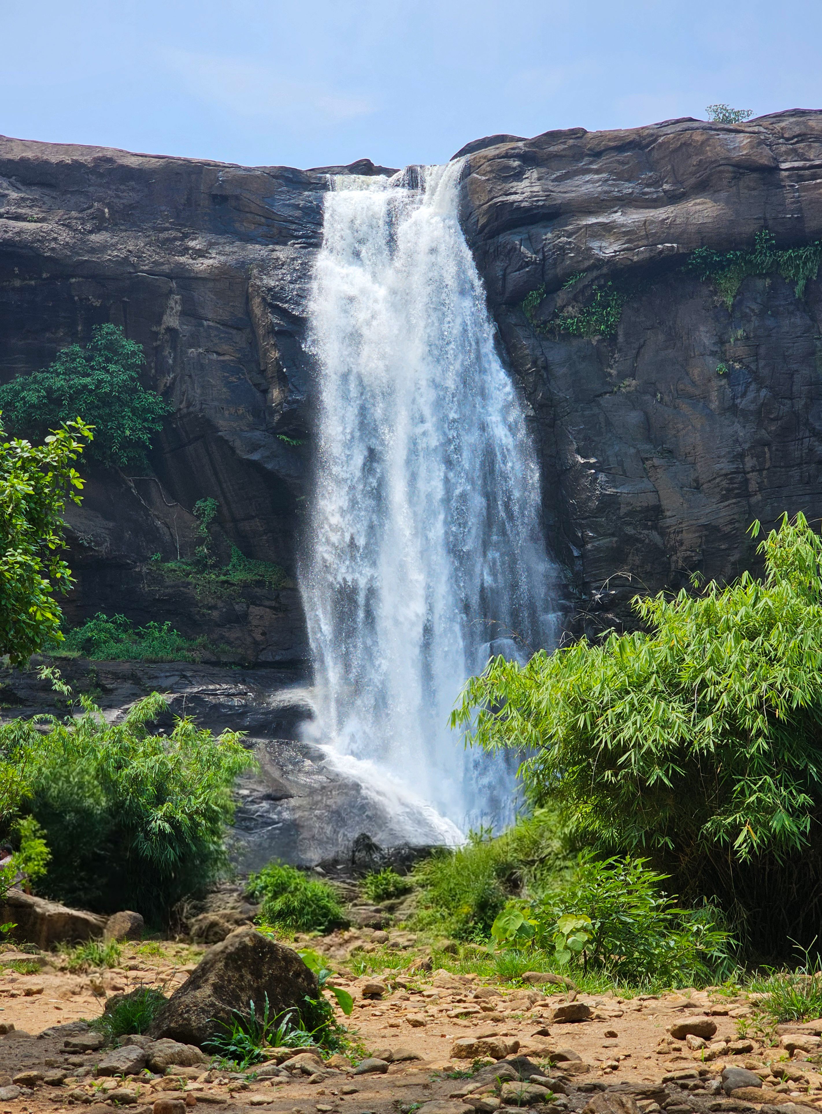 A majestic waterfall cascades down rocky cliffs surrounded by vibrant greenery.