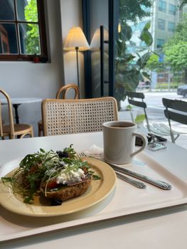 Inviting cafe setting with avocado toast and coffee by a bright window.