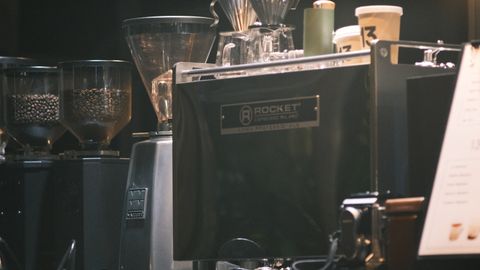 Close-up of an espresso machine in a cafe with coffee grinders and cups.