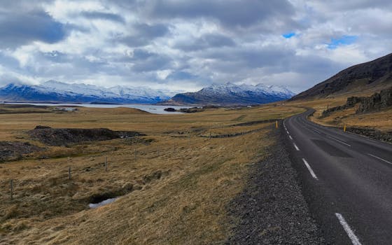 Breathtaking view of mountains and winding road under cloudy skies in Þingeyjarsveit, Iceland.