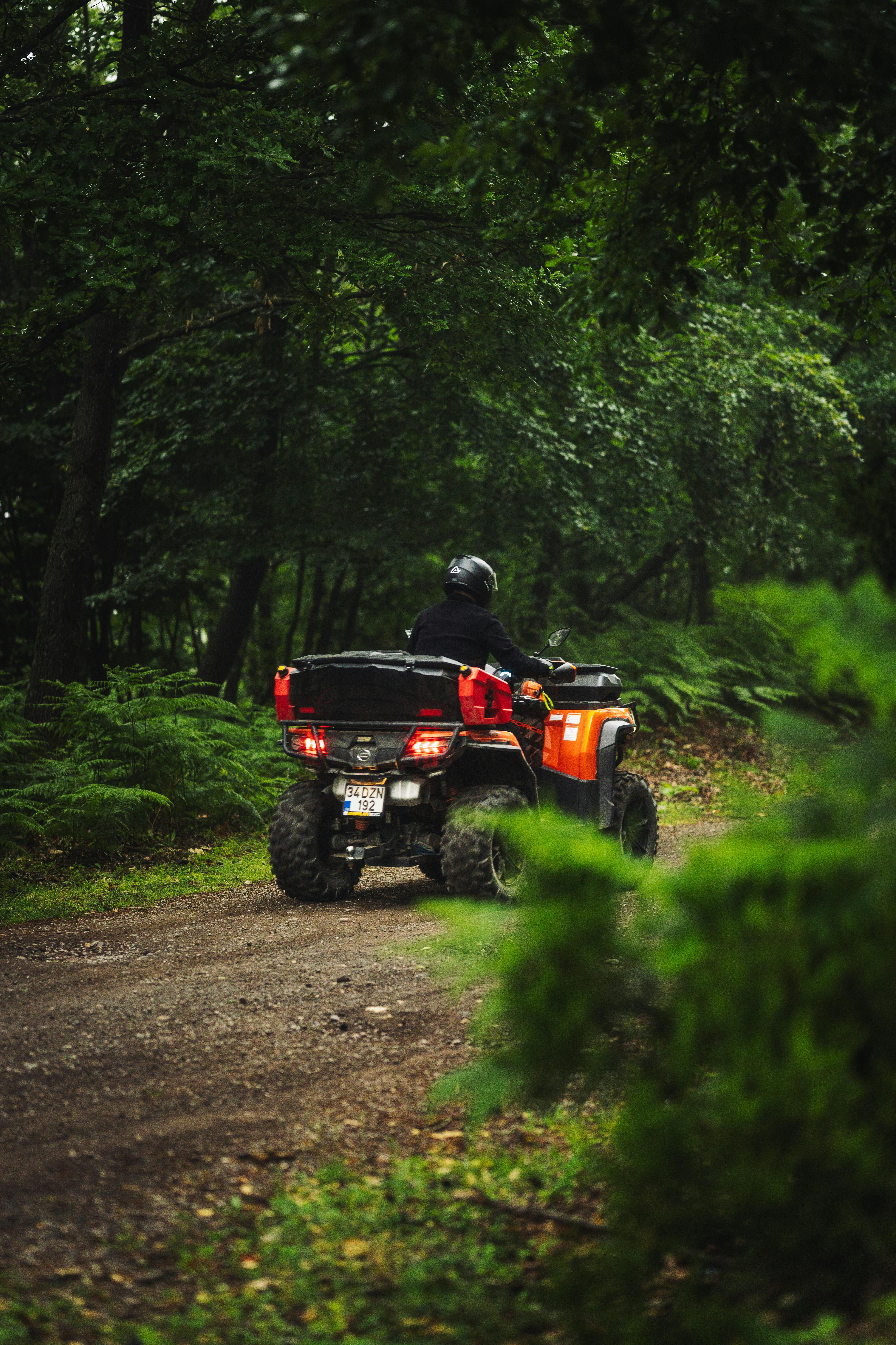 A rider on an ATV navigating a scenic forest trail, surrounded by lush greenery.