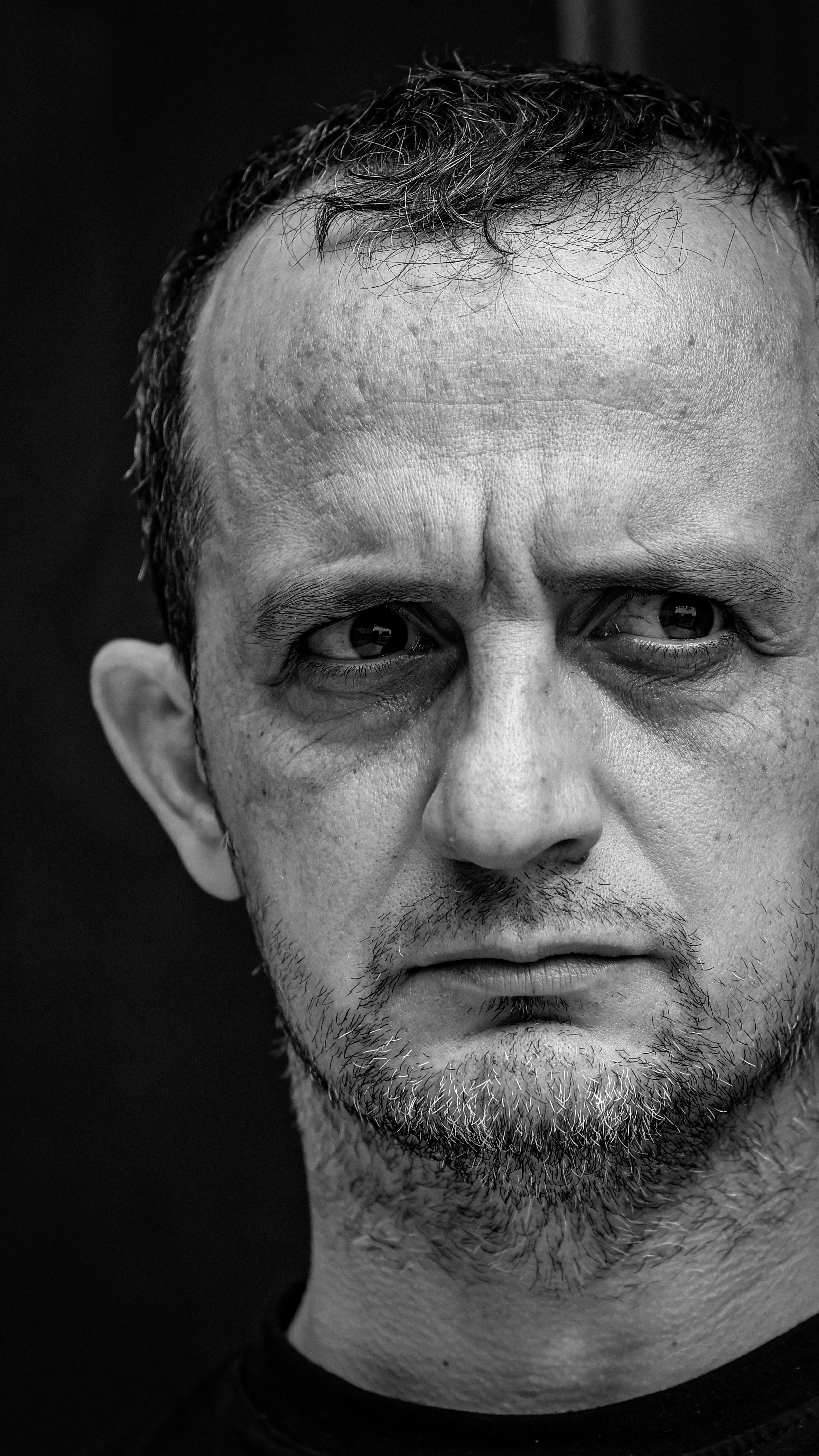 Close-up black and white portrait showing intense emotion in adult male's eyes.