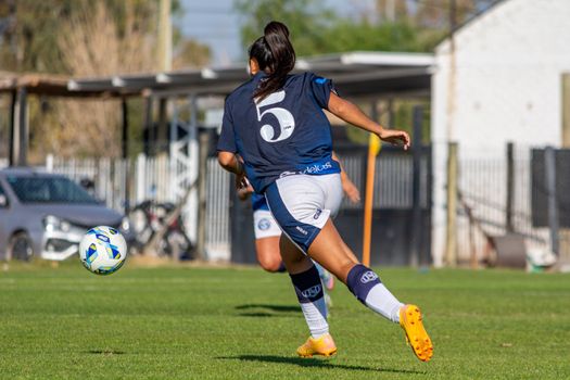 Action shot of a female soccer player in motion with a ball on the field during a game.