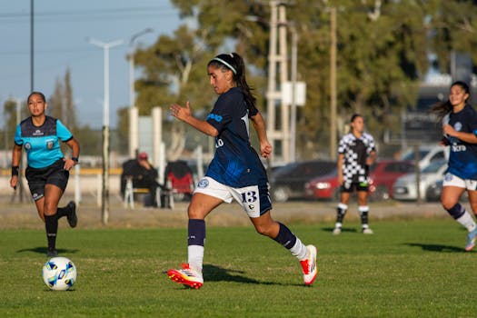 Focused female soccer player in action during an outdoor match, displaying athleticism and determination.