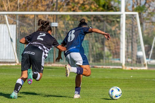 Dynamic shot of female soccer players in action during a match on a sunny day.