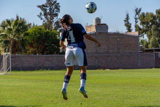 Football player back view heading the ball during practice on a sunny day.