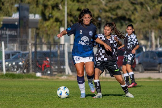 Dynamic action shot of female soccer players competing outdoors on a sunny day.