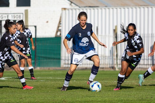 Female football players in action during a match, displaying skill and teamwork on the field.