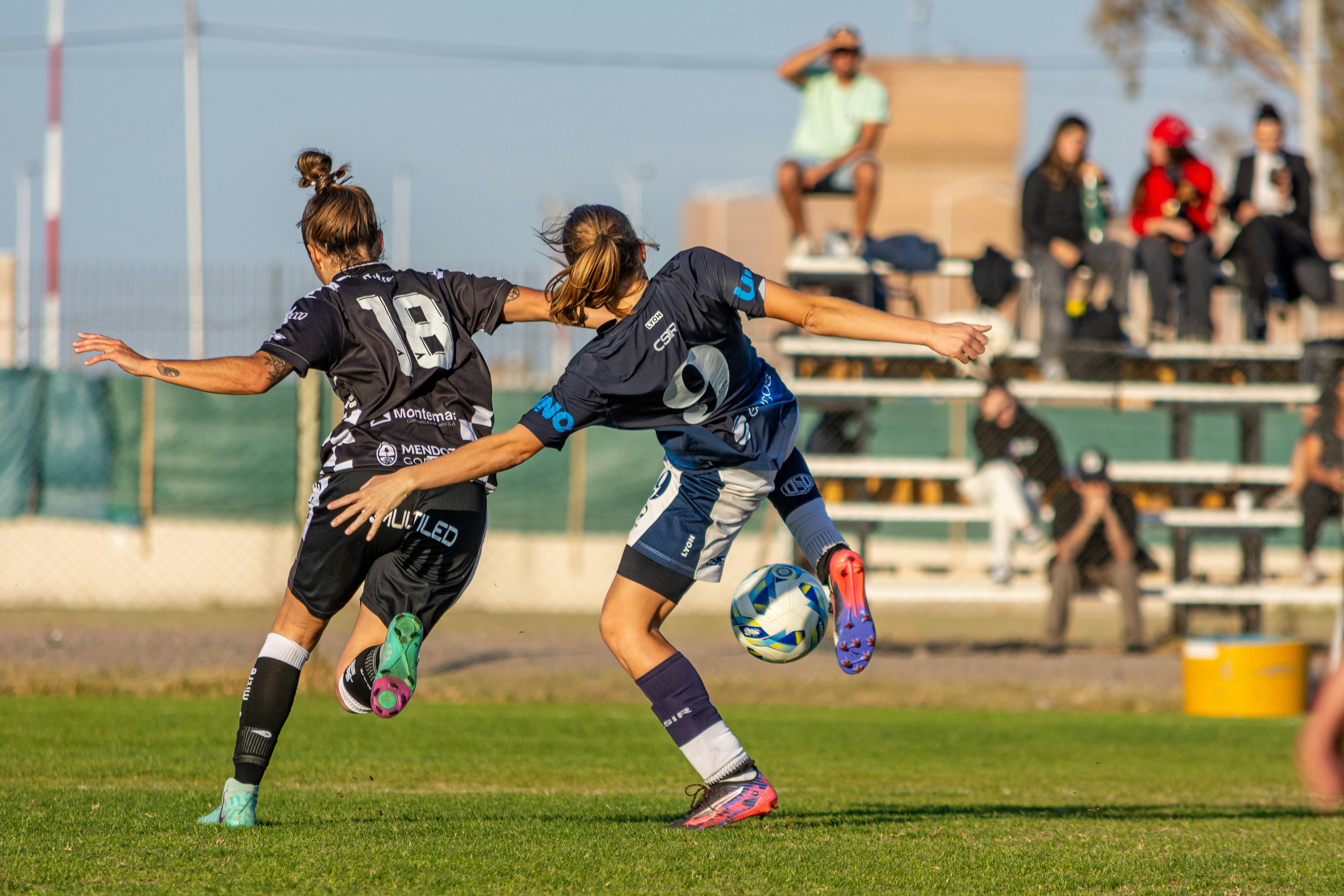 Dynamic action shot of two female footballers competing on the field.