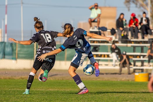 Dynamic action shot of two female footballers competing on the field.