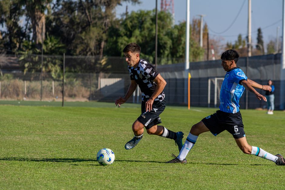 Two soccer players fiercely competing on a sunny field during an exciting match.