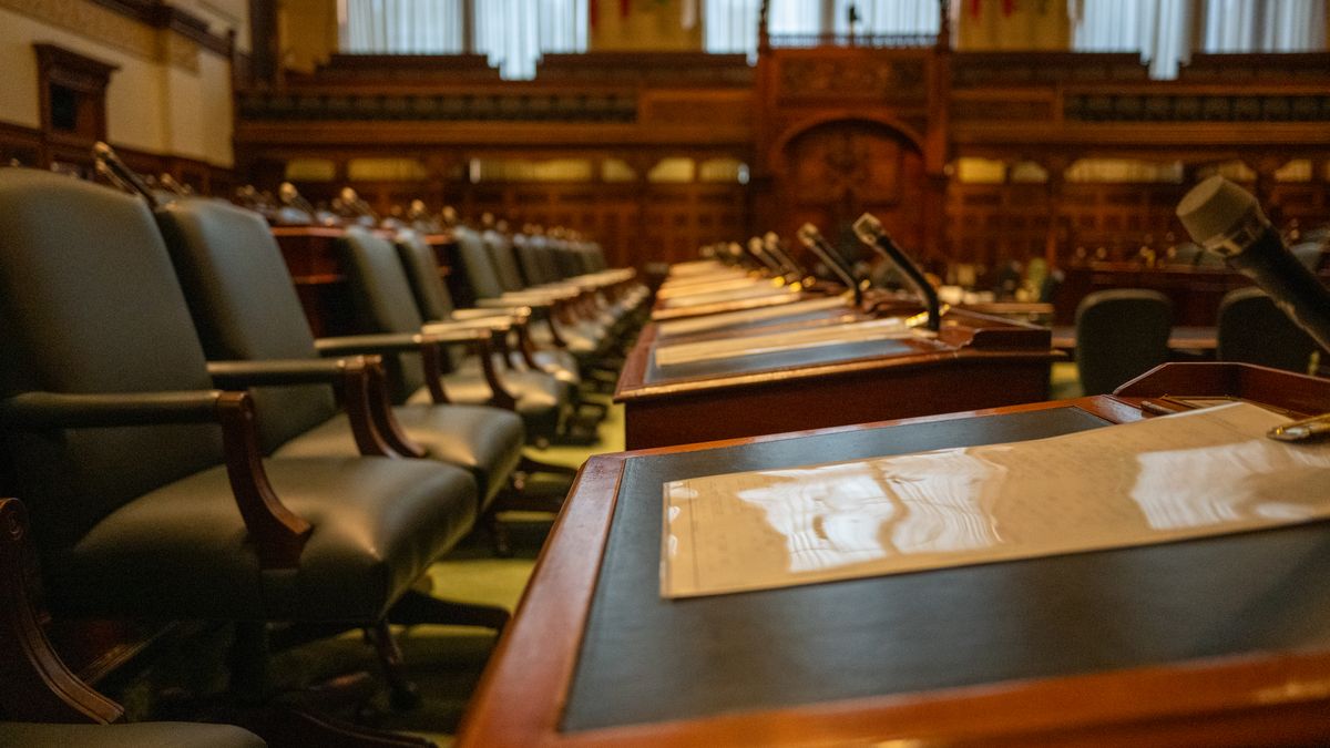 A detailed view of an empty legislative chamber with rows of desks and microphones, evoking governance.