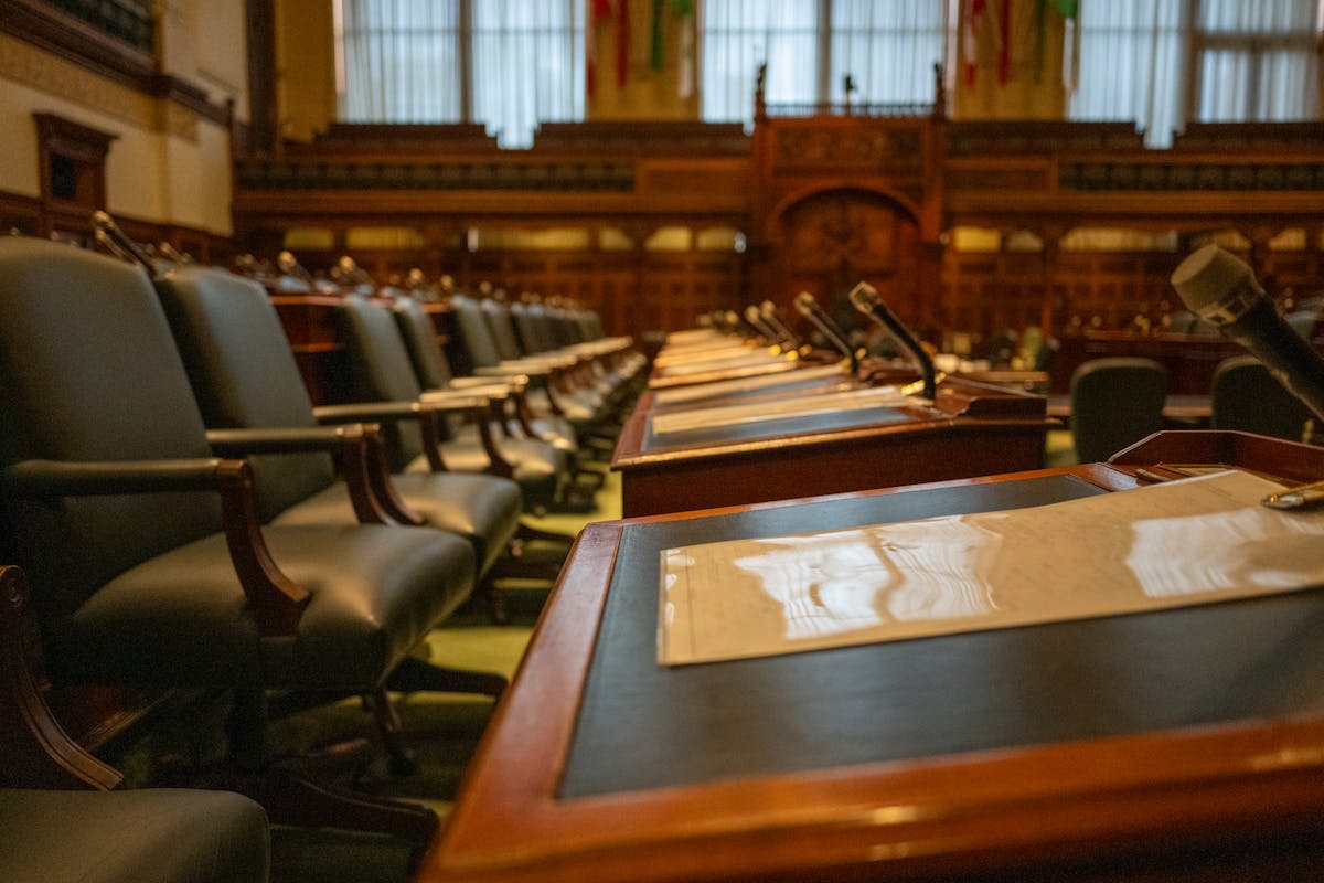 A detailed view of an empty legislative chamber with rows of desks and microphones, evoking governance.