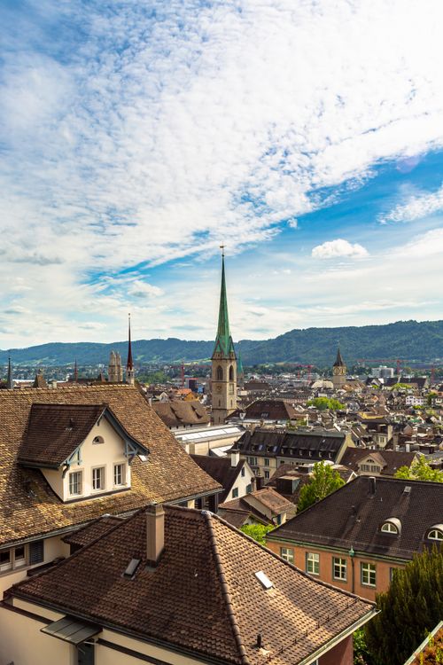 Free Aerial view of Zürich showcasing historic architecture and the iconic Fraumünster Church under a bright blue sky. Stock Photo