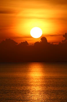 Beautiful orange sunset casting reflections over calm ocean waves.