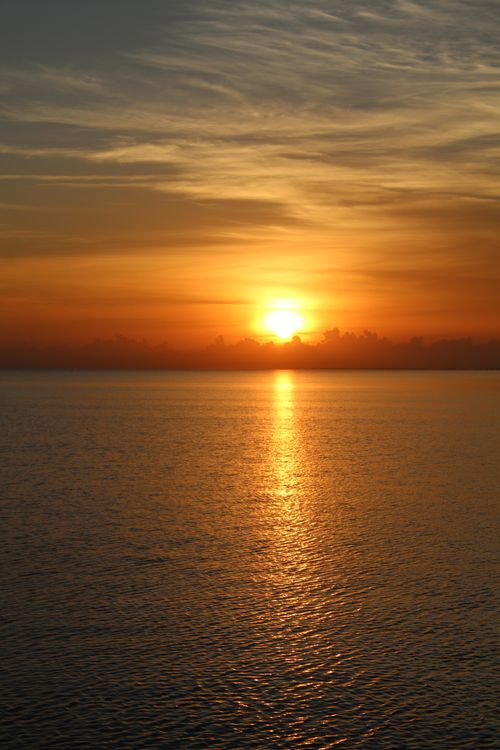 Free Vibrant sunset over a calm ocean, perfect for tranquility and relaxation themes. Stock Photo