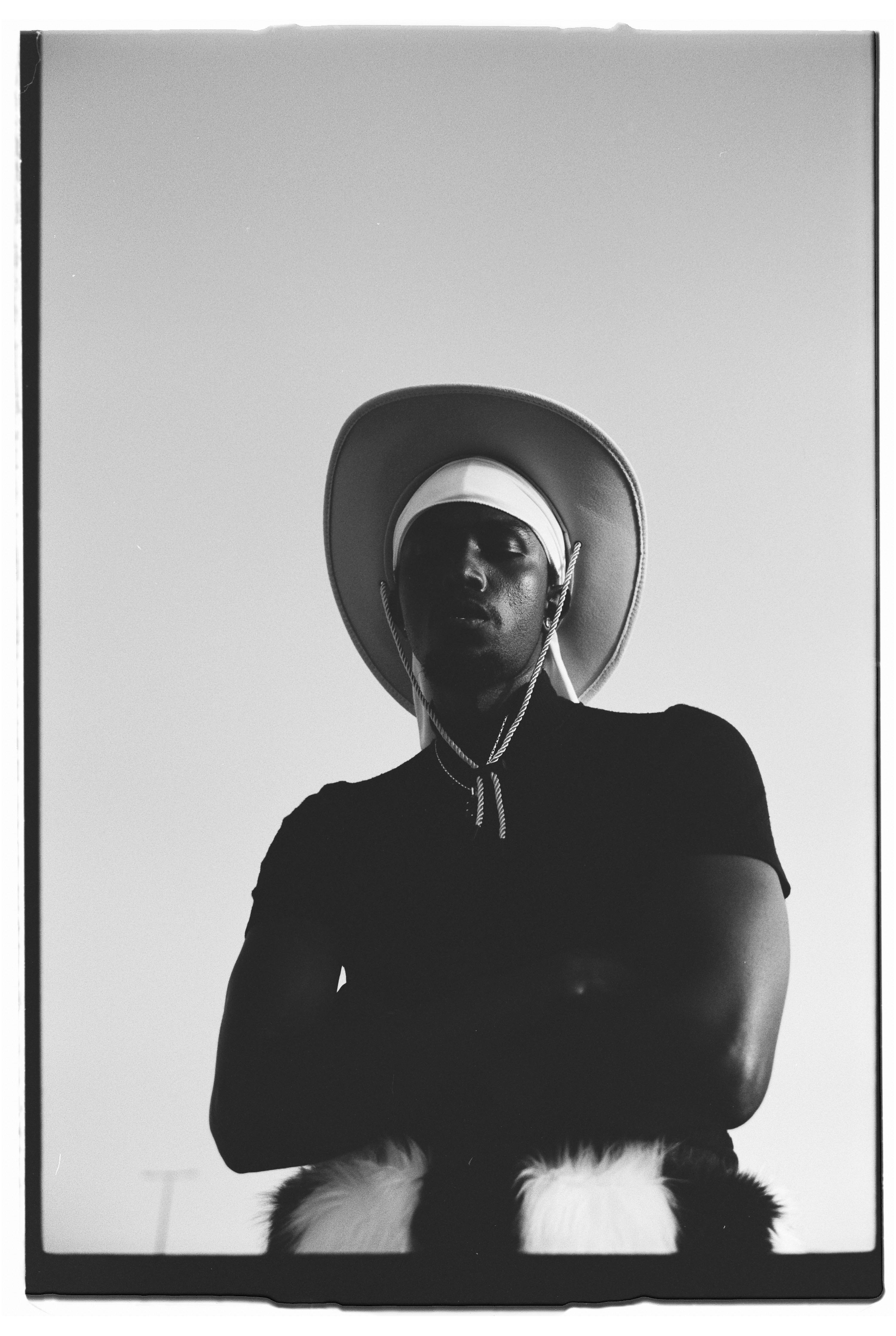 Black and white portrait of a person wearing a cowboy hat with dramatic lighting.