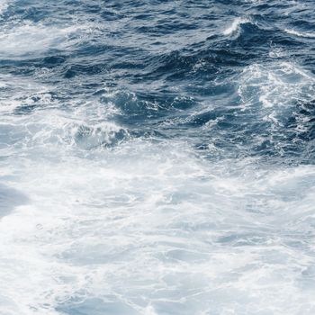 High-angle view of ocean waves with white foam creating a dynamic and dramatic sea scene.