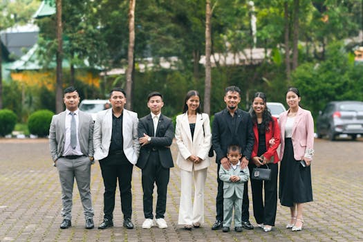 Seven individuals in formal attire pose outdoors, smiling and standing in a row.