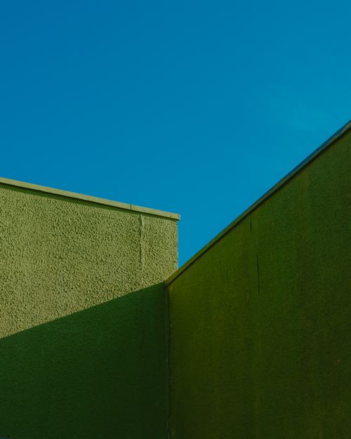 Free Contemporary green building facade with clear blue sky background, showcasing minimalist design in Chillán, Chile. Stock Photo