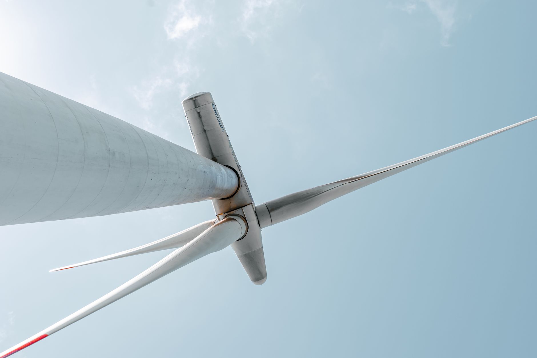Looking up at a majestic wind turbine under a clear blue sky, showcasing renewable energy innovation.