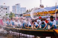 Vibrant boat race with participants splashing water during a lively competition outdoors.