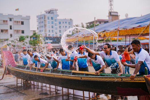 Participants splash water during a vibrant boat race festival in a bustling city environment.