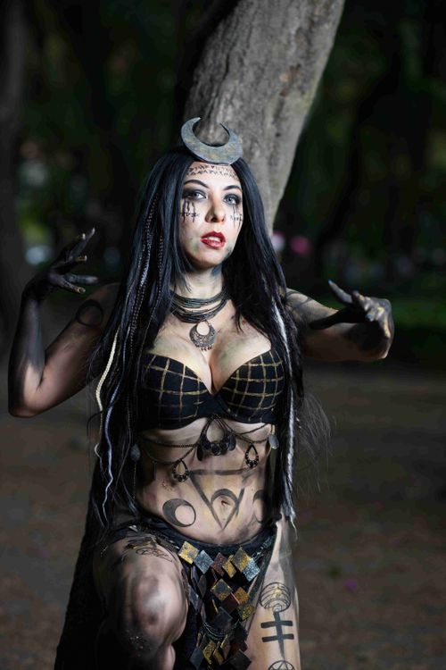 Free Mysterious female cosplayer with dark makeup poses in forest, embodying fantasy character. Stock Photo