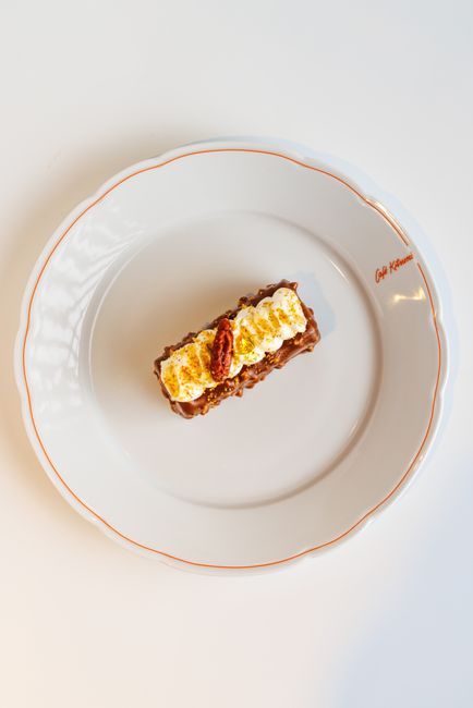 A slice of chocolate poke cake lifted from a baking dish, showing caramel-soaked layers under a swirl of whipped topping and crushed toffee bits.