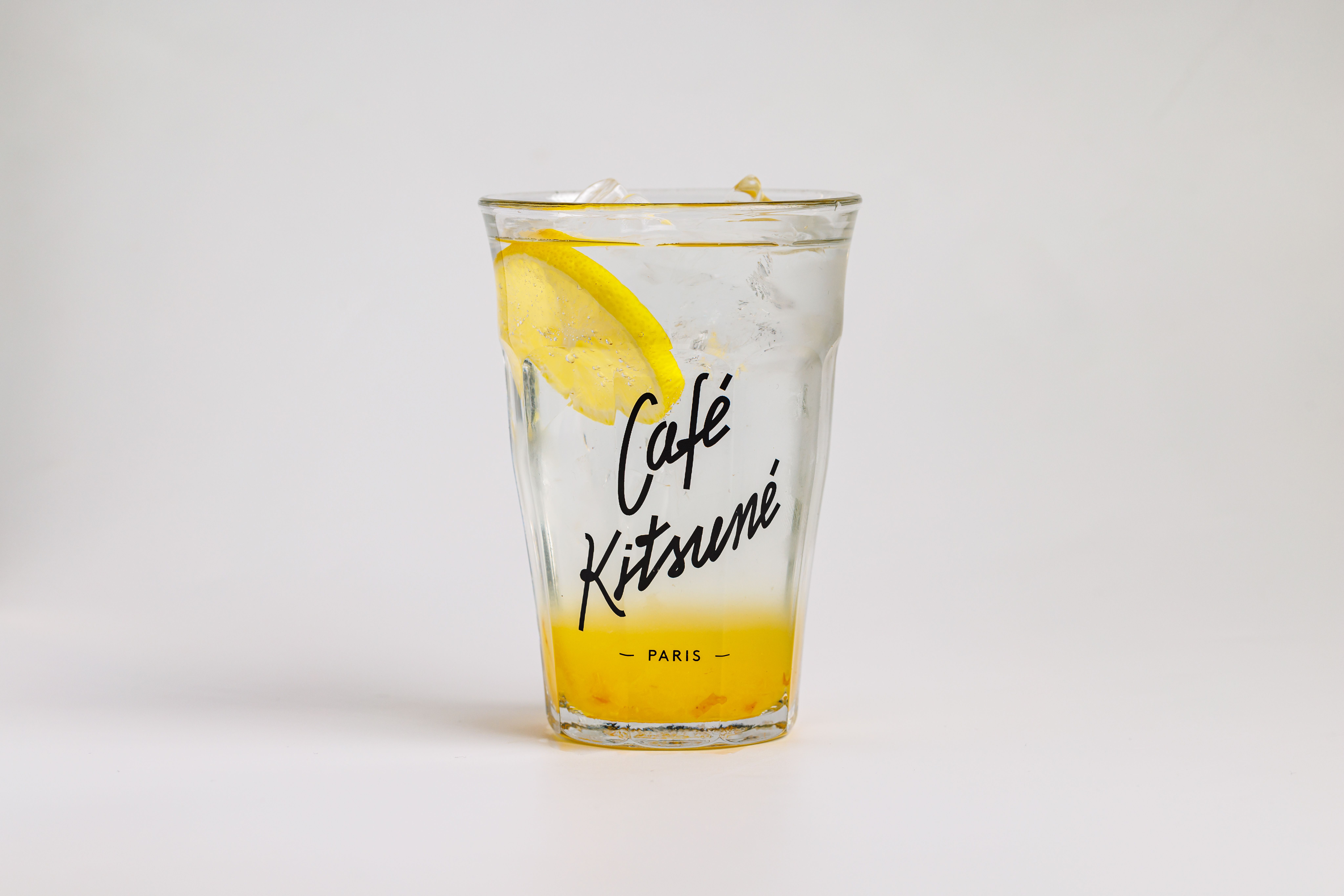 Refreshing lemonade in a Café Kitsuné glass with ice and lemon slice.