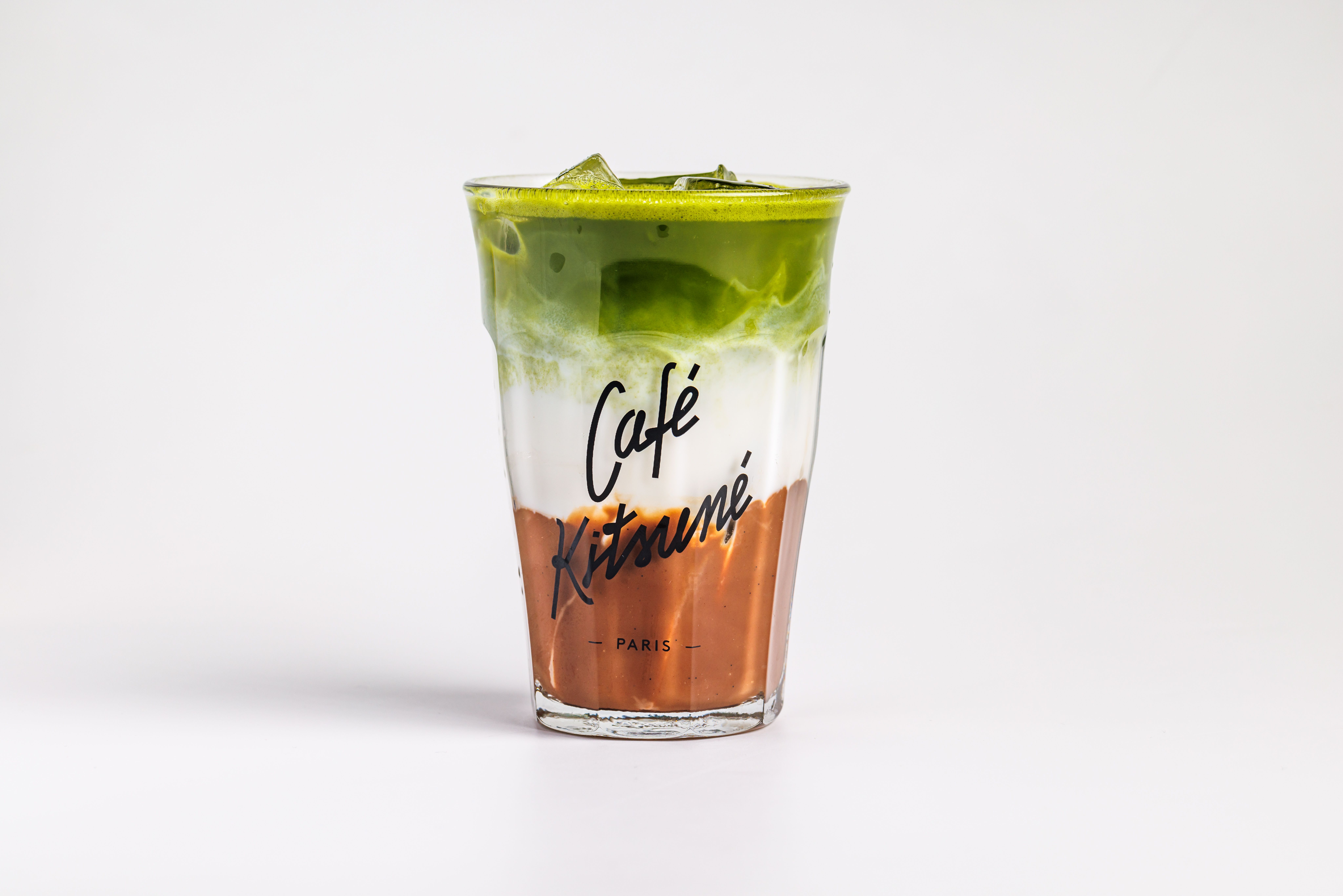 De franc Latte de matcha gelat i colorit en una tassa de vidre de la marca Cafe Kitsune, artísticament disposada en capes. Foto d'estoc