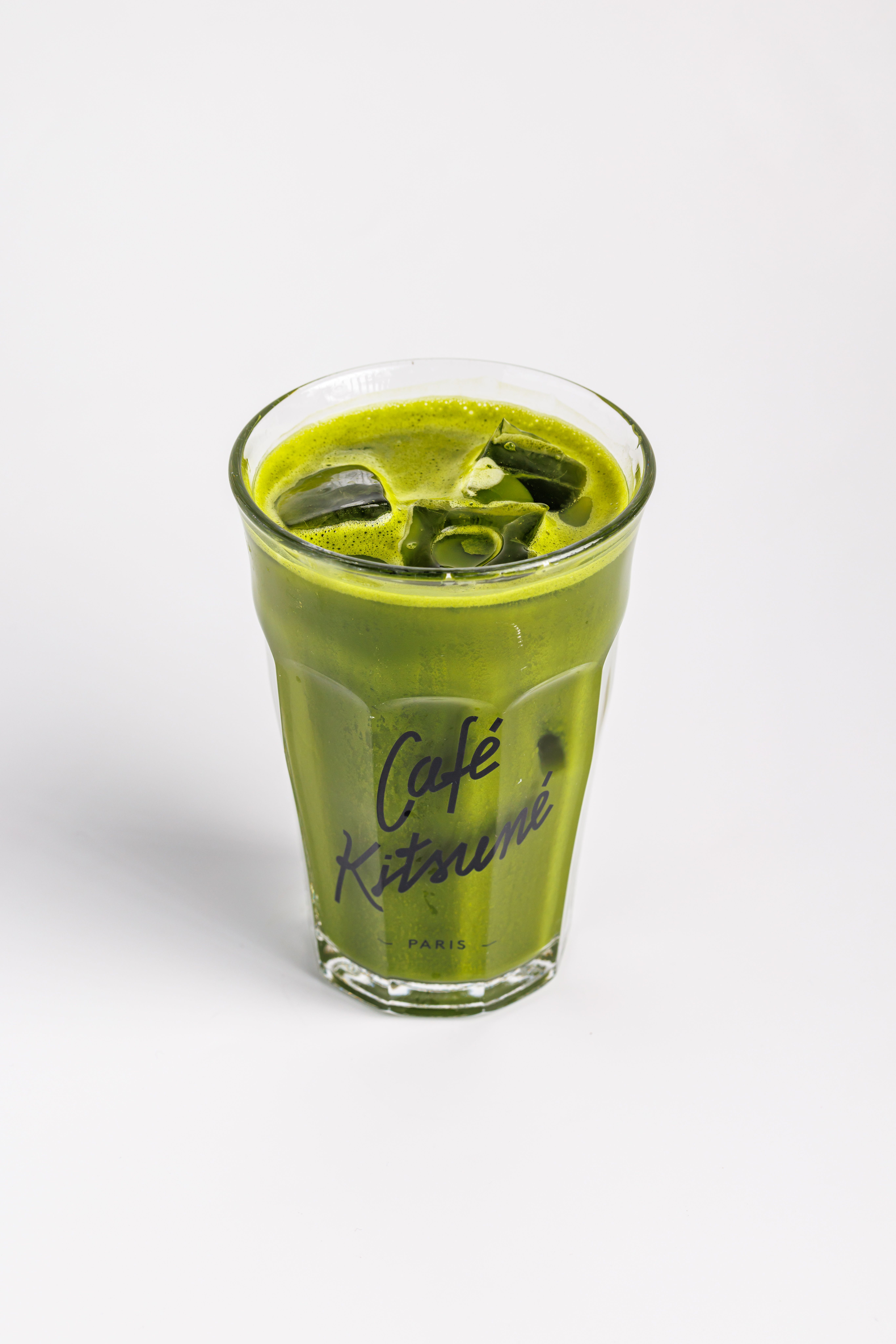 De franc Un vibrant cafè amb llet matcha gelat en un got de la casa Café Kitsuné sobre fons blanc. Foto d'estoc