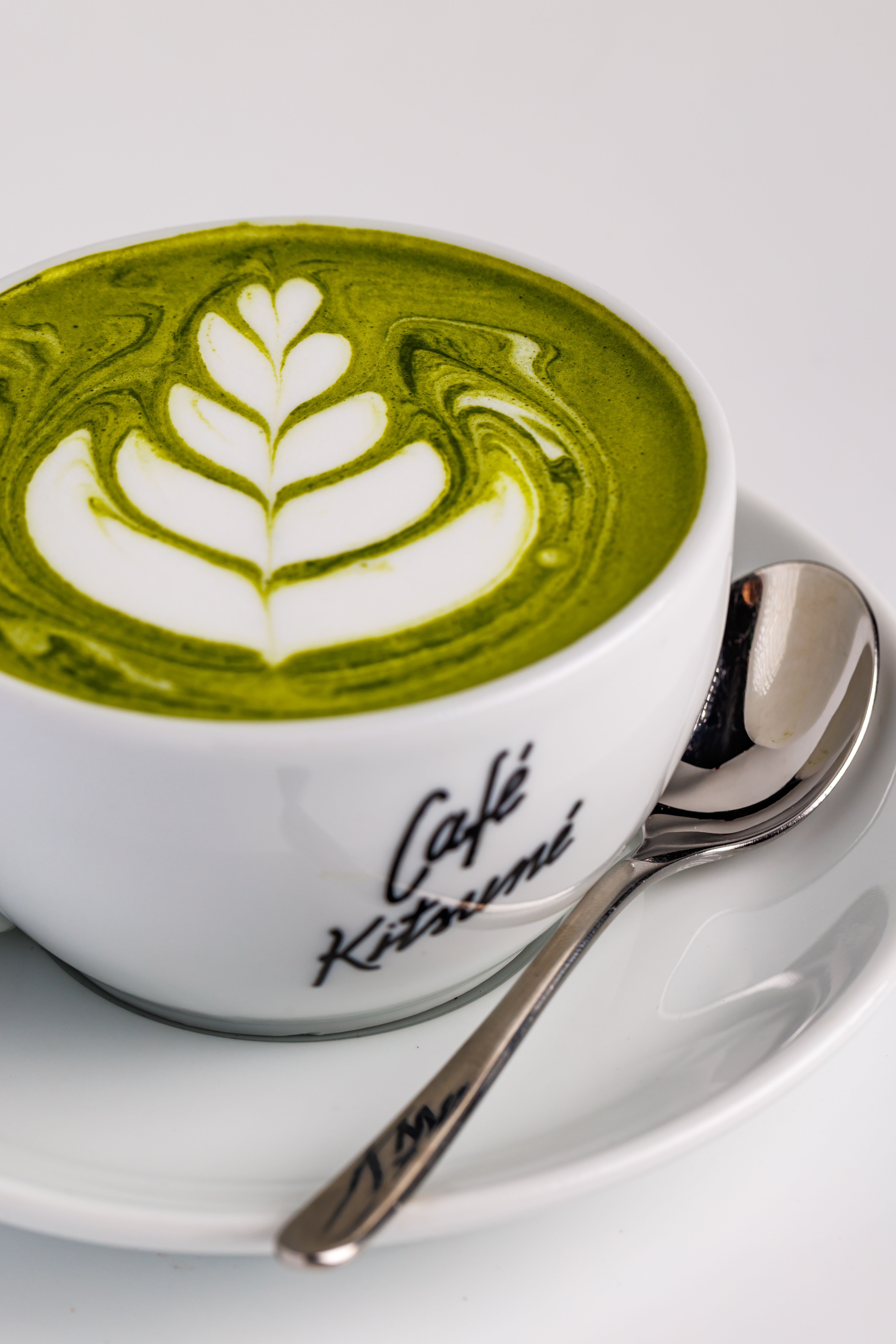 De franc Elegant cafè amb llet matcha amb art de fulles en una tassa de cafè de marca. Foto d'estoc