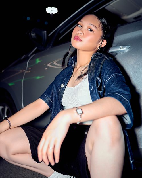 Free Young woman in urban attire posing by a car under night lights. Confident modern style. Stock Photo