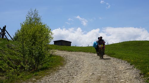 Free Two people riding a motorbike on a rural dirt road under a clear spring sky. Stock Photo
