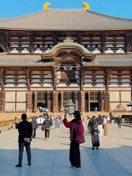 Visitors taking photos at a historic temple in Japan, capturing cultural architecture.