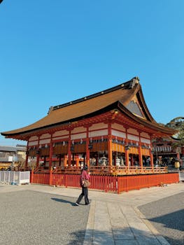 A beautiful traditional Japanese shrine under a clear blue sky with a wooden and red structure.