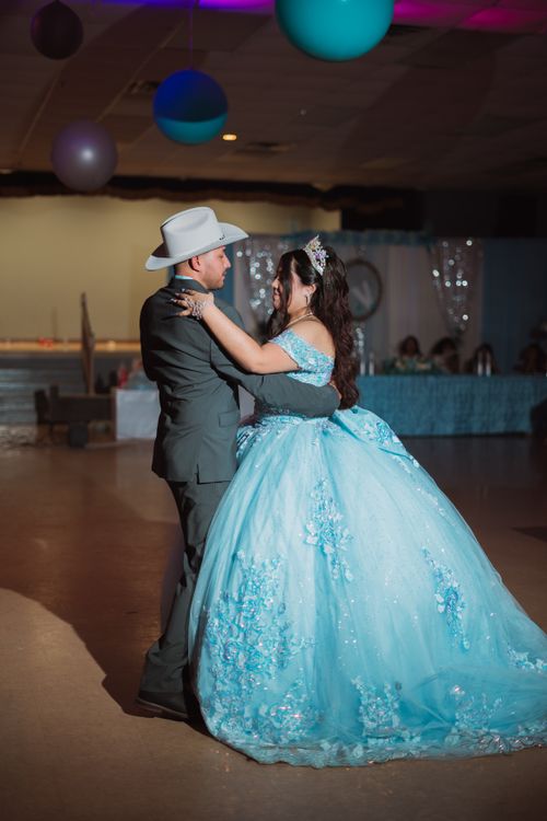 Free A beautiful quinceañera dance scene featuring a girl in a stunning blue gown with a cowboy partner, indoors. Stock Photo
