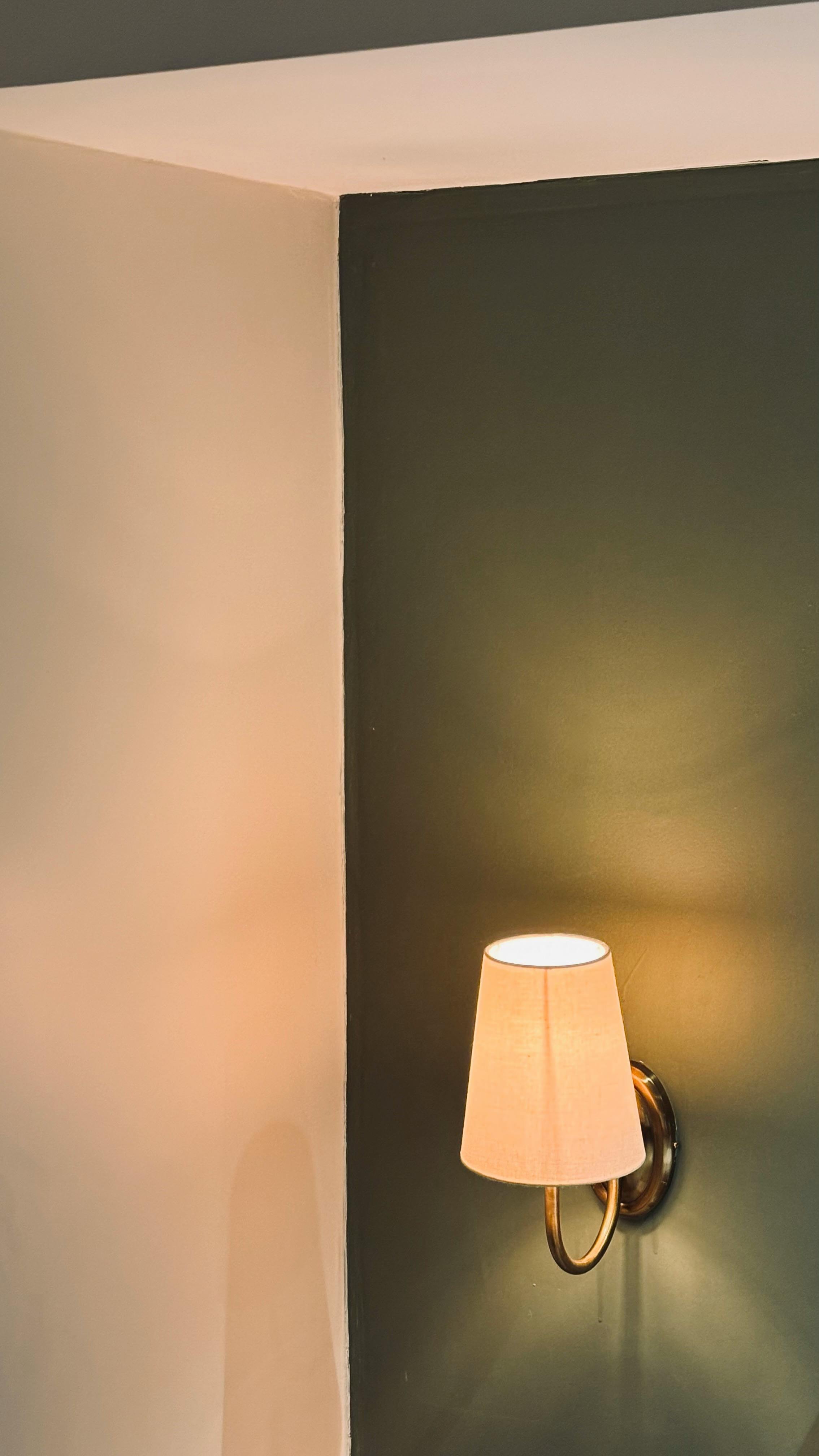 Zadarmo Elegantná nástenná lampa vrhá teplé svetlo na dvojfarebnú stenu a zvýrazňuje minimalistický štýl dekorácie. Fotka z fotobanky