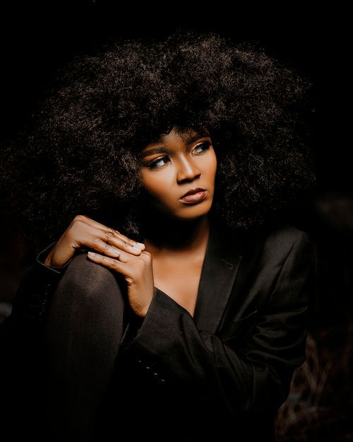 Free Fashionable woman in black with curly hair in a moody portrait. Stock Photo