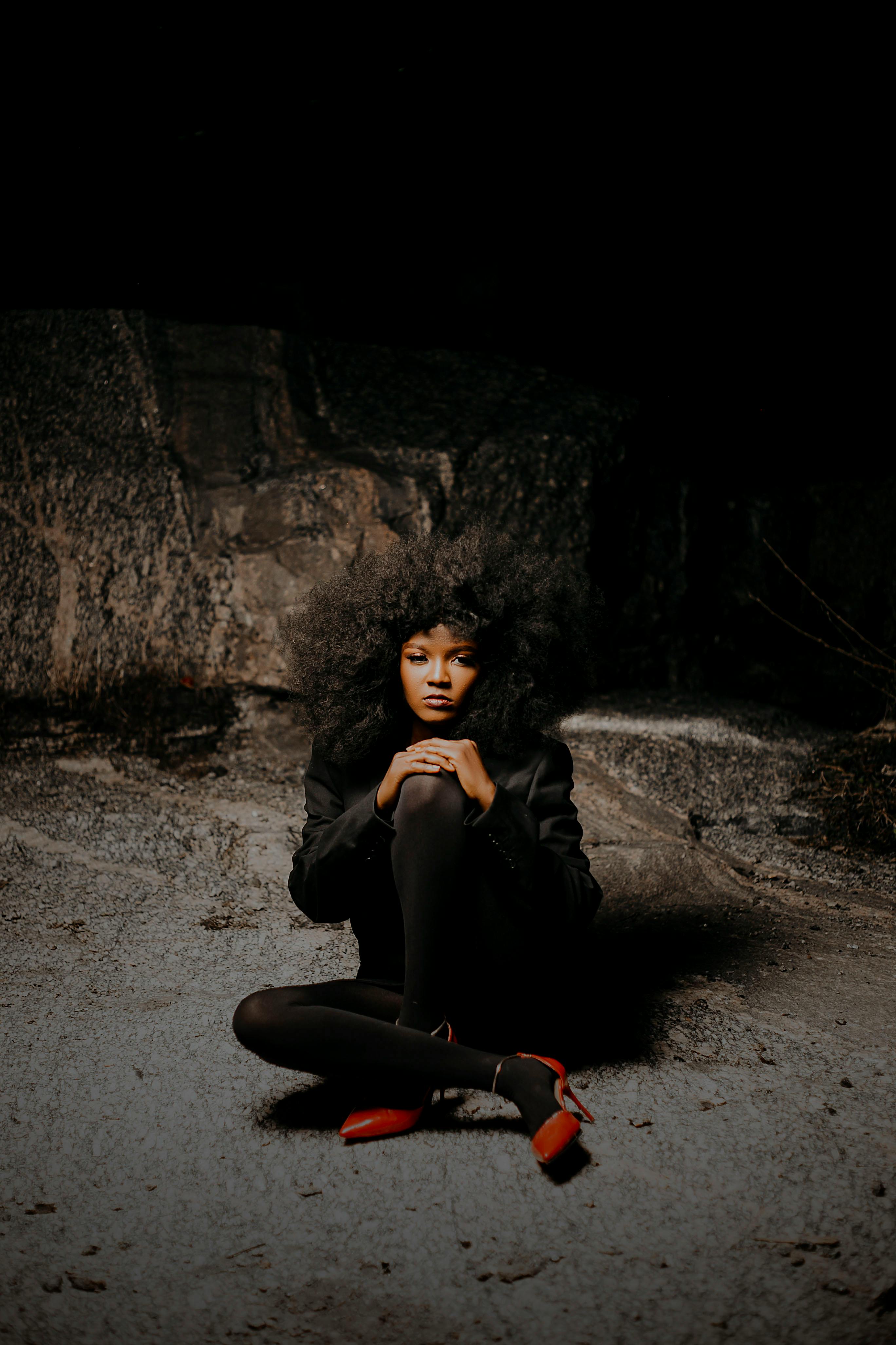 A woman sitting on gritty urban surface, dramatic lighting.