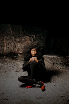 A woman sitting on gritty urban surface, dramatic lighting.