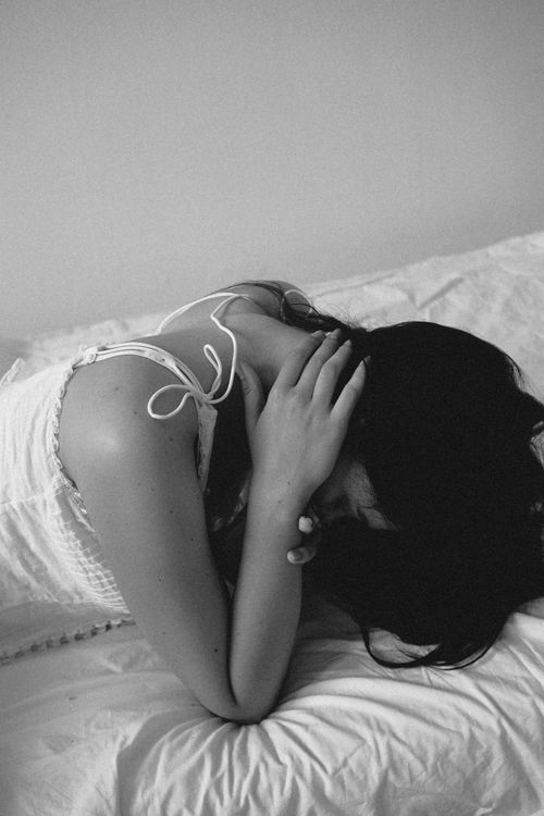 Free Black and white portrait of a woman in distress, lying on a bed. Stock Photo