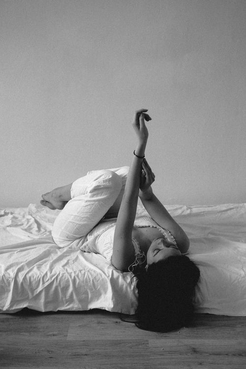 Free Artistic black and white portrait of a woman relaxing on a bed. Minimalist and serene. Stock Photo
