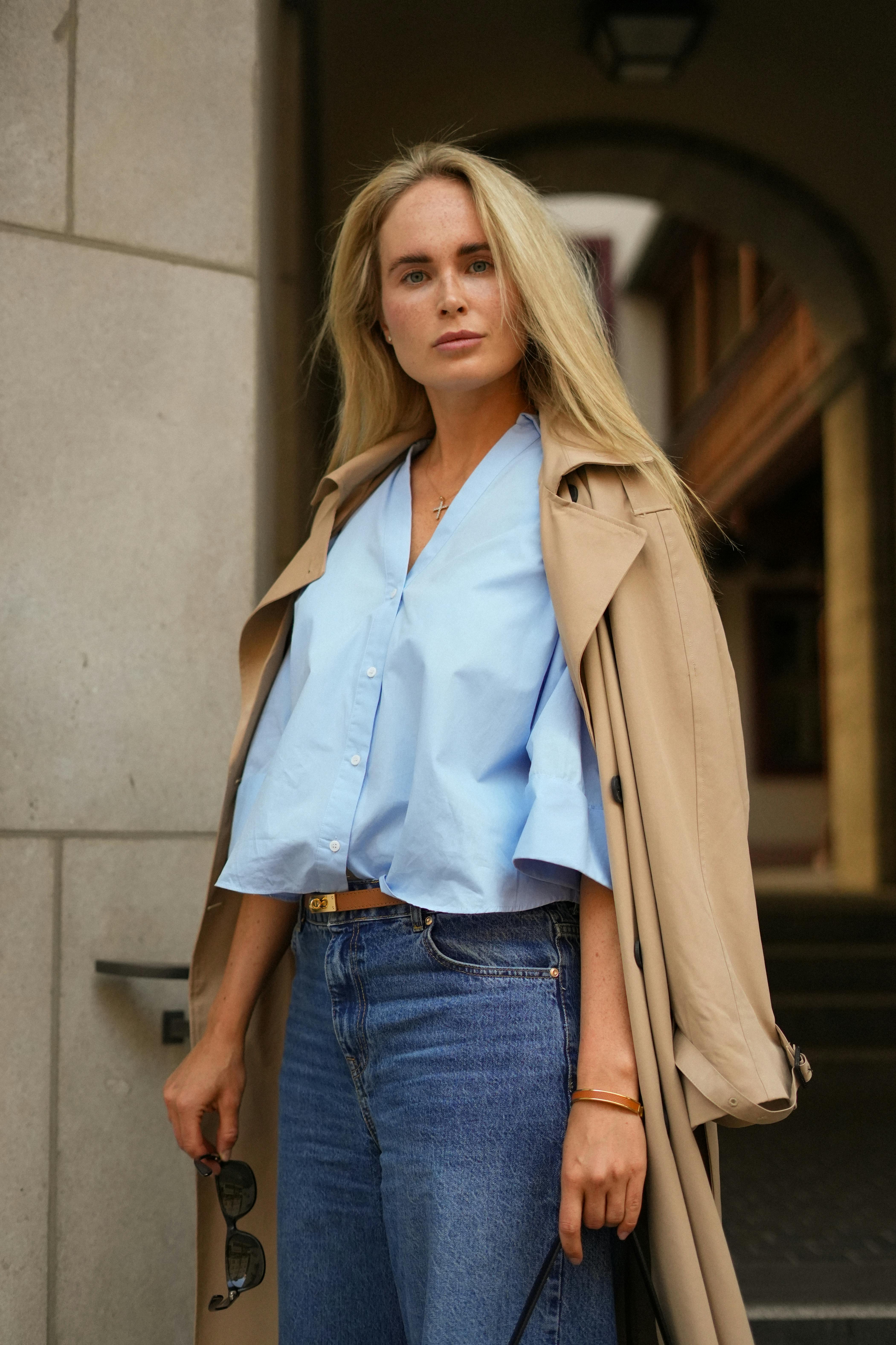 免費 身穿風衣和牛仔褲的時尚女性站在城市街道上。 圖庫相片