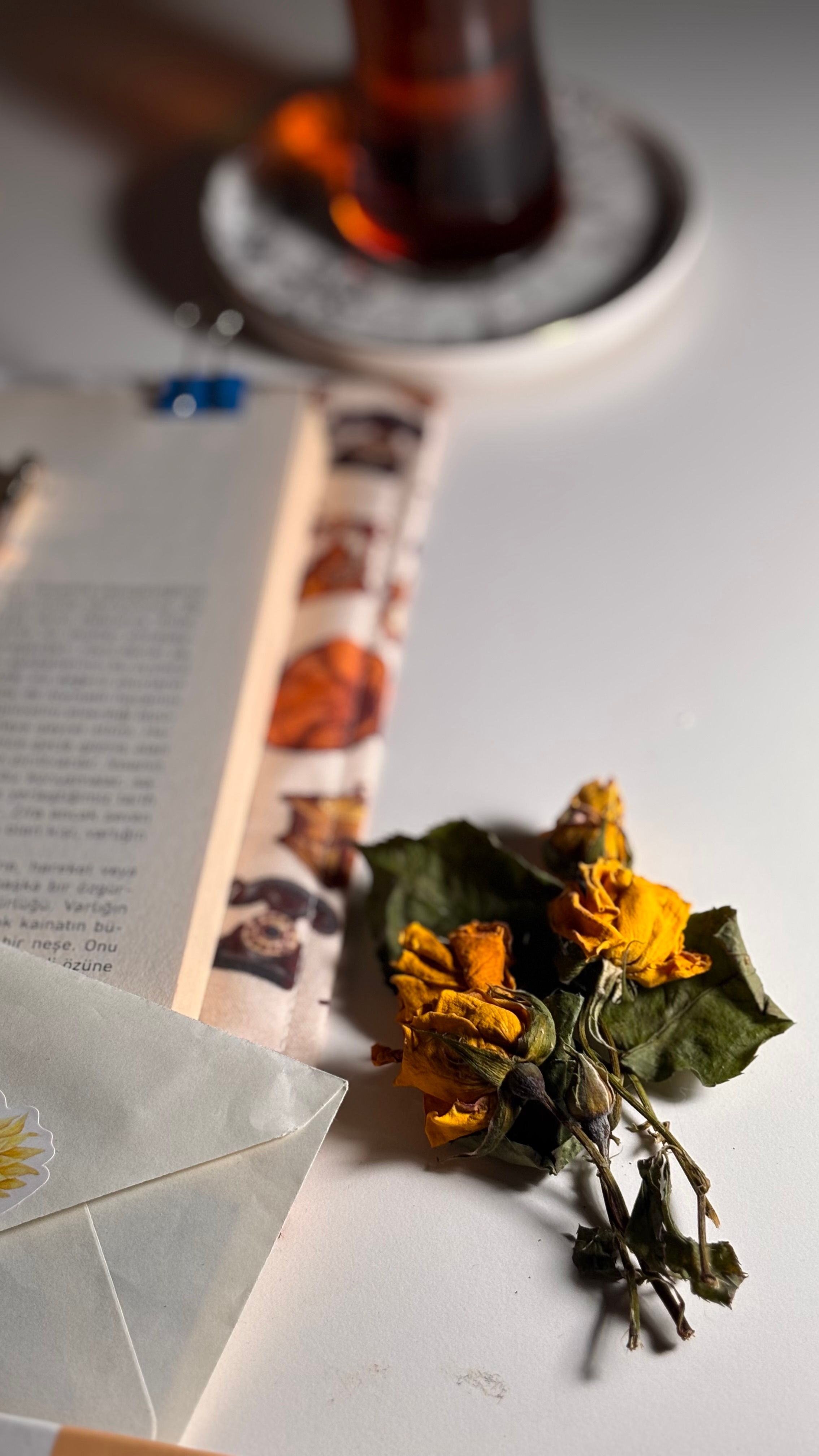 Aesthetic flat lay of dried flowers, book, and tea cup on a table, capturing a cozy ambiance.