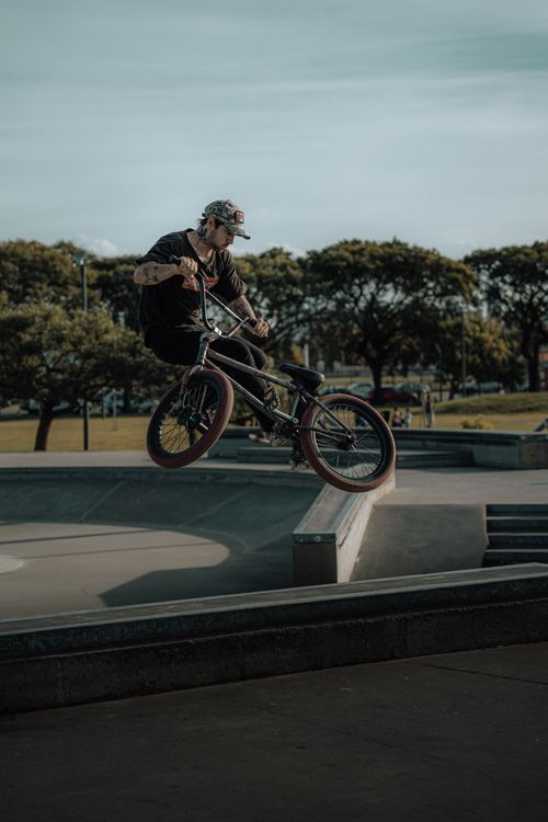 Free Man performing a BMX stunt in an outdoor skatepark, showcasing extreme sports skills and agility. Stock Photo