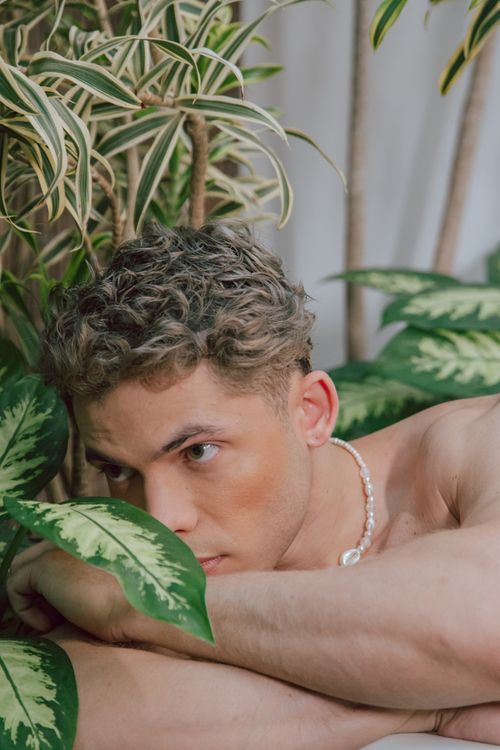 Free Young man relaxes surrounded by lush indoor plants, creating a tranquil atmosphere. Stock Photo