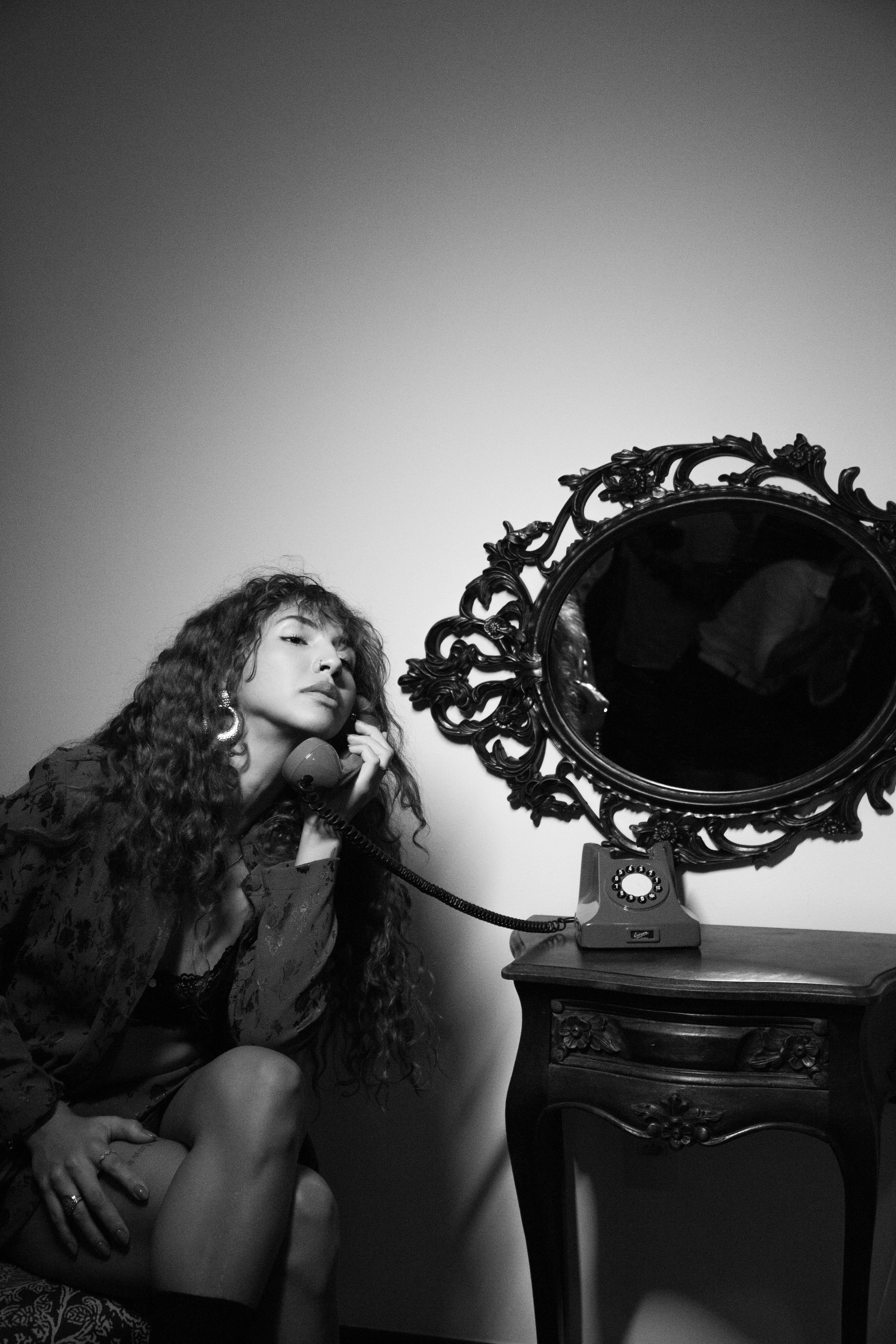 Stylish woman in a vintage setting, using a rotary phone, adds a nostalgic vibe.